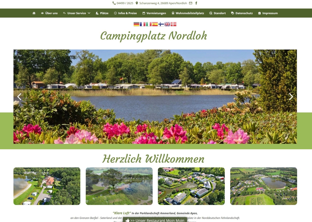 Aussicht auf einen Campingplatz an einem Seeufer, umgeben von Blumen und Bäumen.